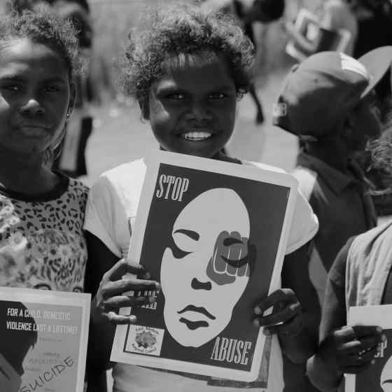 Children hold signs standing up against family violence. 
